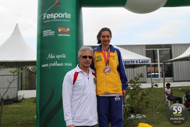 Diretor técnico da FME de Brusque, Delmar Tondolo, entrega medalha para Naiana Baumgratz, prata nos 3 mil metros